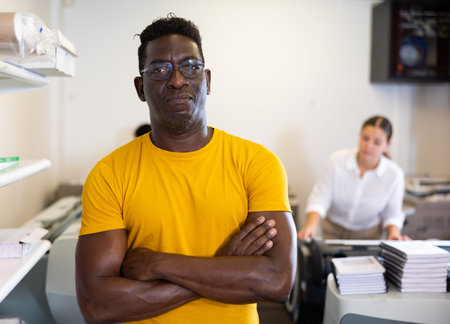 Portrait of middle-aged male with crossed hands on chest in the printer shop