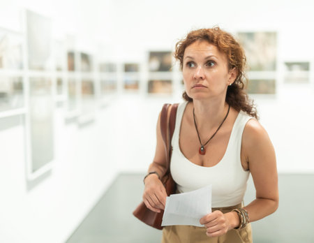Woman observing photographs on display in photo gallery