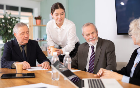 Elderly man leading meeting with senior colleagues at table