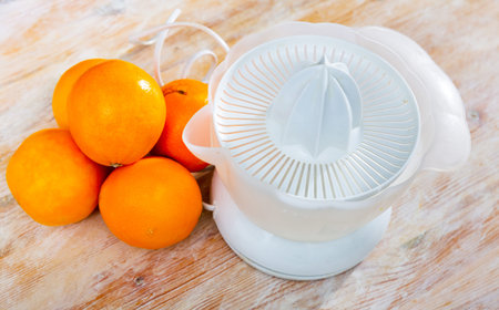 View of a citrus juicer with oranges lying next