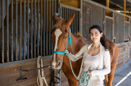 Young woman leads horse out of stable