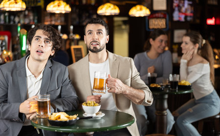 Group of friends hangs out at sports bar, watching teams match