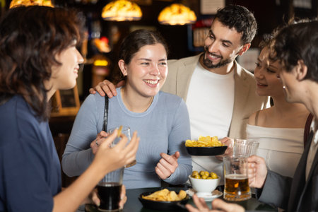 Group of friends at bar talking and drinking beer
