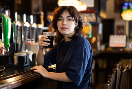 Portrait of a woman with glass of drink at bar counter
