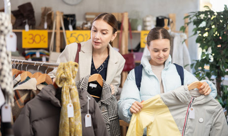 woman and her daughter choose a down jacket in a storeの写真素材