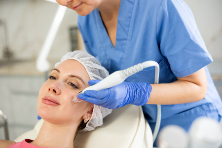 Young visitor receiving hardware electric massage and absorb blackheads and deeply clear skin by...