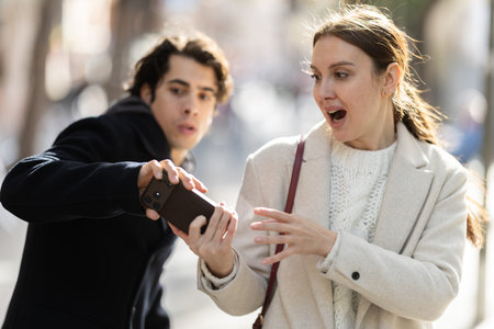 Male thief trying to snatch mobile phone of frightened woman on city