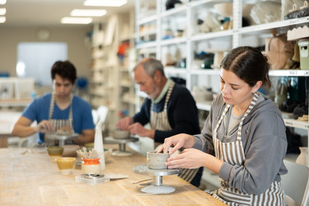 Young woman sculpts ceramic piece in workshop