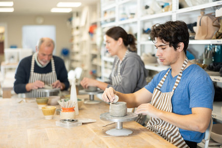 Young man sculpts ceramic piece in workshop