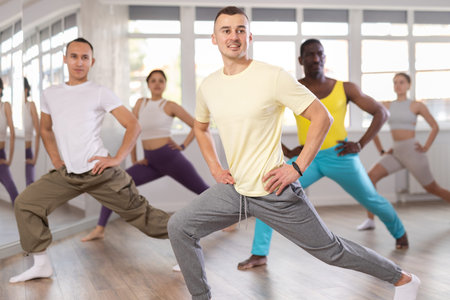 Cheerful young multinational people training synchronous group choreography in dance studio