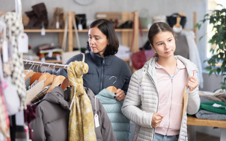 Teenage girl with her mother try on down jacket