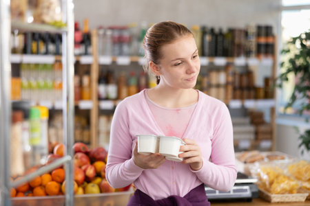Woman chooses tasty yogurt to buy in the grocery department section of storeの写真素材
