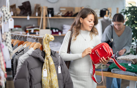Selective young girl choosing handbag in clothing store