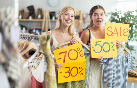 Young women holds yellow poster informing about discounts in store