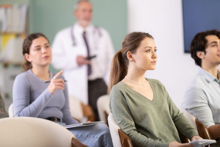 Female student listening to a lecture against the background of a doctor
