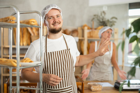 Content young man worker stands with his back to frustrated girl behind bakery counter