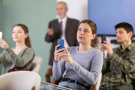 Young girl scanning QR-code with mobile devices during presentation