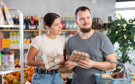 Husband and wife choose mushrooms together in supermarket - family chooses mushrooms: oyster mushrooms or champignonsの写真素材