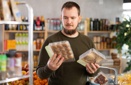Grocery shopping at supermarket - man chooses mushrooms: oyster mushrooms or champignons