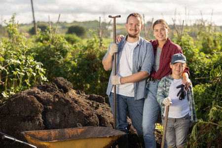 Man woman and boy at wheelbarrow with soil