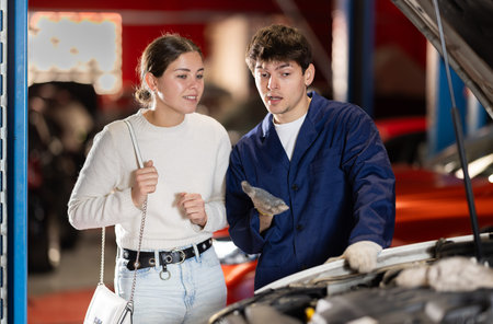Mechanic checking young woman client car in car service center