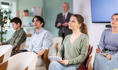 Students listening in lecture hall with professor in backgroundの写真素材