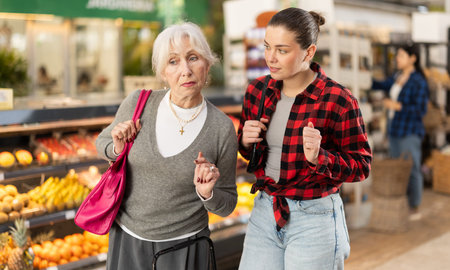 Young and elderly woman choosing groceries at storeの写真素材