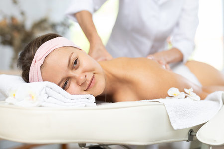 Close-up of young woman getting back and shoulder massageの写真素材