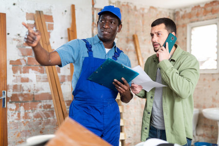 Worker and owner building discuss construction plan inside building under constructionの写真素材