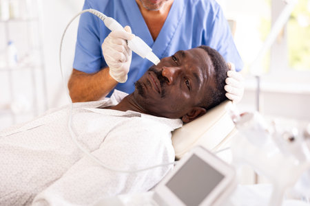 African American experiencing facial skin peeling using ultrasonic scrubberの写真素材