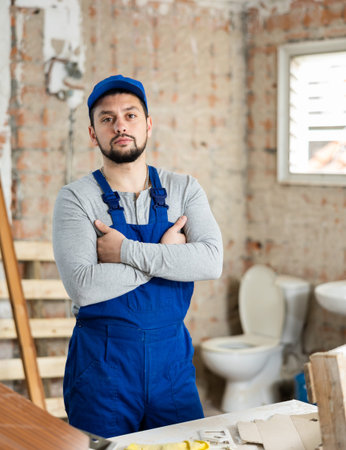Portrait of builder man in blue overalls in room being renovatedの写真素材