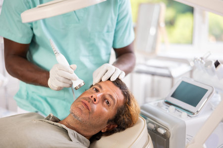 Adult man undergoing high frequency ultrasound facial treatmentの写真素材