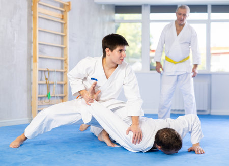 Men train to throw on the mat under the guidance of judo coachの写真素材