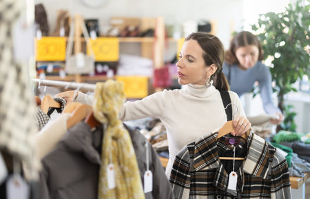 Middle-aged woman choosing winter coat in clothing store