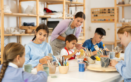 Children painting ceramics with a teacher