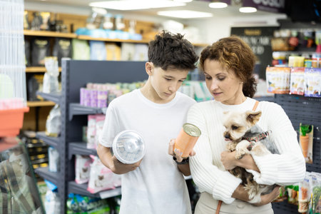 Mother with dog Yorkshire Terrier in arms and son carefully examine label on dry dog food