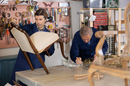 Confident craftsman in process of creation wooden furniture in workshop