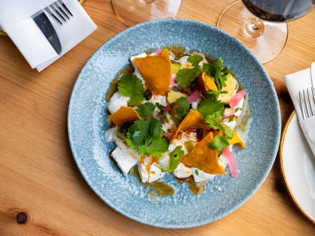 Salad with burrata cheese, avocado, greens and tortilla chips