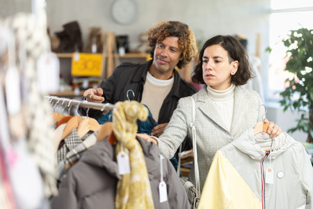 woman chooses jackets and coats next to a man who advises