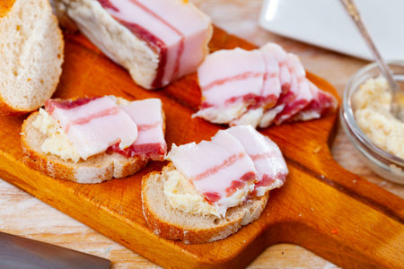 Snack for vodka, homemade salo with bread and horseradish on rustic board