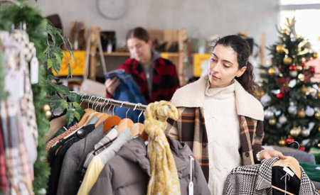 Young Armenian girl choosing coat in clothing store