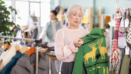 Mature woman select fashionable sweater in clothing store