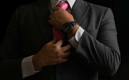 Successful businessman on black background, smoking and tieの写真素材