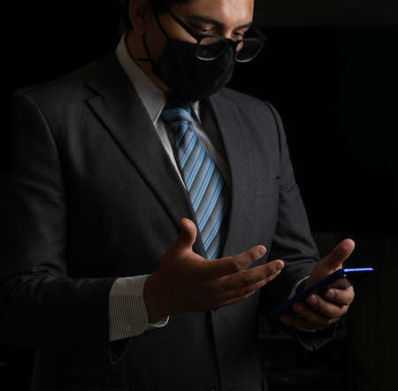 Successful businessman on black background, smoking and tieの写真素材