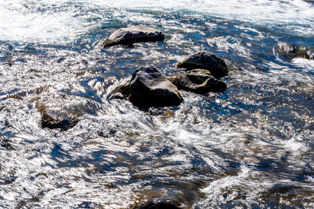 Creek or stream water flowing past rocks and stonesの写真素材