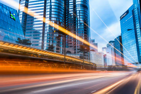 Street traffic at night in Hong Kong. Office skyscraper buildings and busy traffic on highway road with blurred car light trails. Hong Kong.のeditorial素材