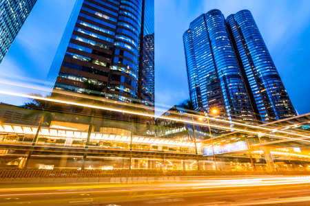 Street traffic at night in Hong Kong. Office skyscraper buildings and busy traffic on highway road with blurred car light trails. Hong Kong.のeditorial素材