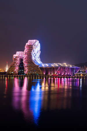 Night view of Kaohsiung Music Center with a view from Love River. The white hexagonal building structure on the riverbank in Kaohsiung, Taiwan.のeditorial素材