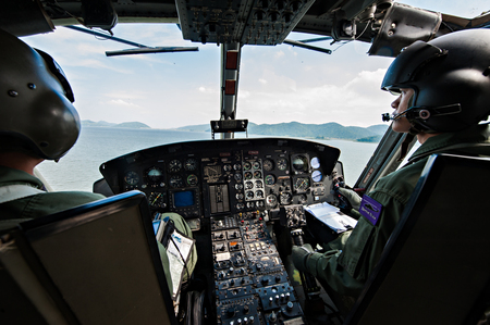 PRANBURI, THAILAND - December 4, 2016 - Cockpit interior details of Army helicopter with pilot and co pilot on board while flying over river. Pilot prepares to land.のeditorial素材