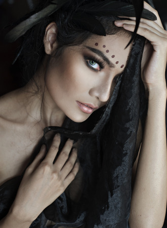 Beauty shot of black long hair Asian woman focus on blue eye in the dark bed room natural window light.の写真素材